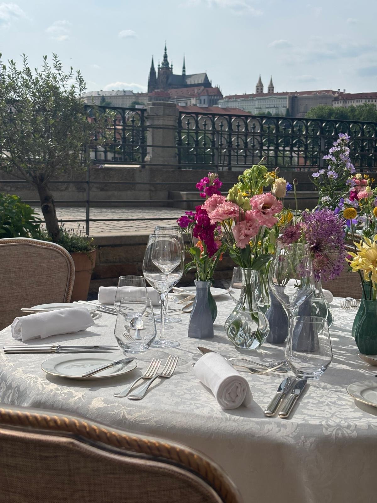 Dinner table set on a terrace overlooking Prague Castle
